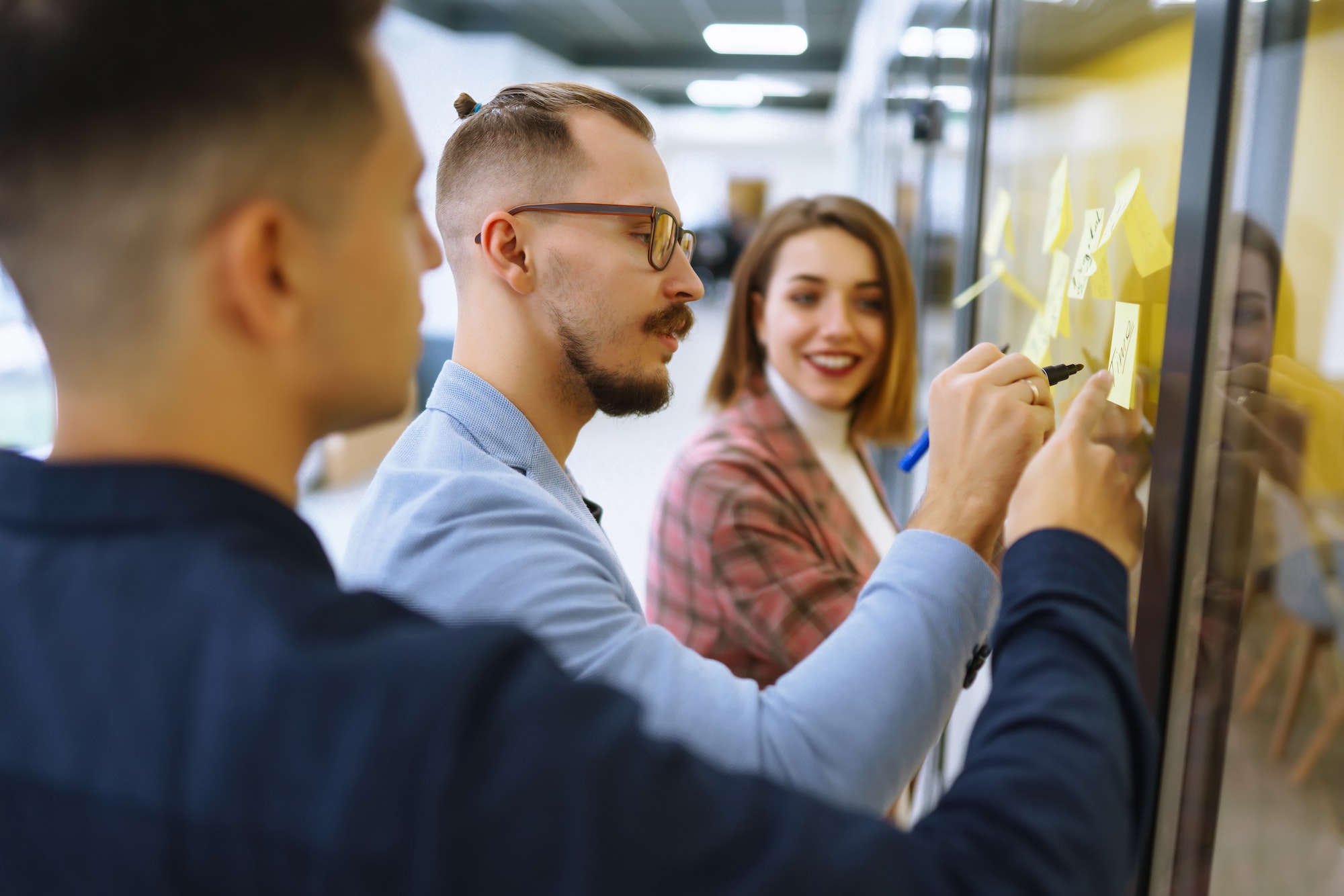 Young business people discussing and planning strategy Front of glass wall marker and stickers.