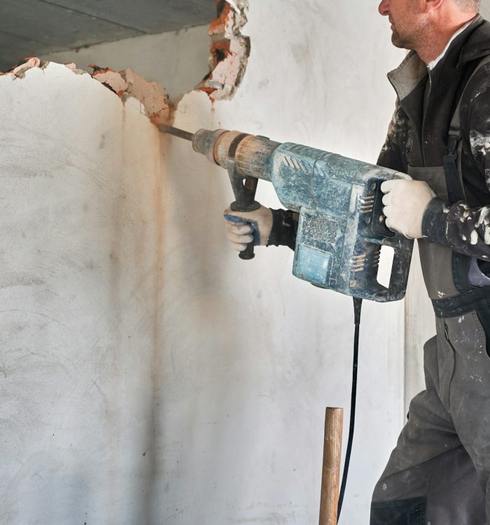 Cropped view worker with perforator during demolition wall.