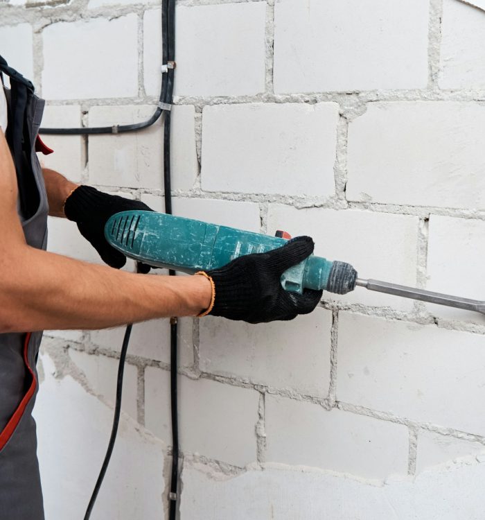 Man with demolition hammer remove stucco from wall. Renovation concept